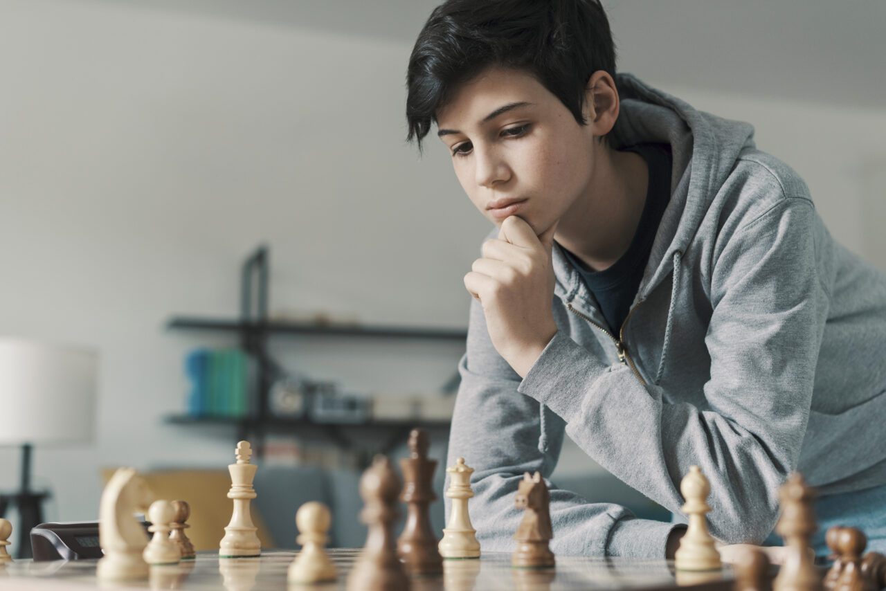 smart-boy-playing-chess-and-staring-at-the-chessboard-e1698161801842